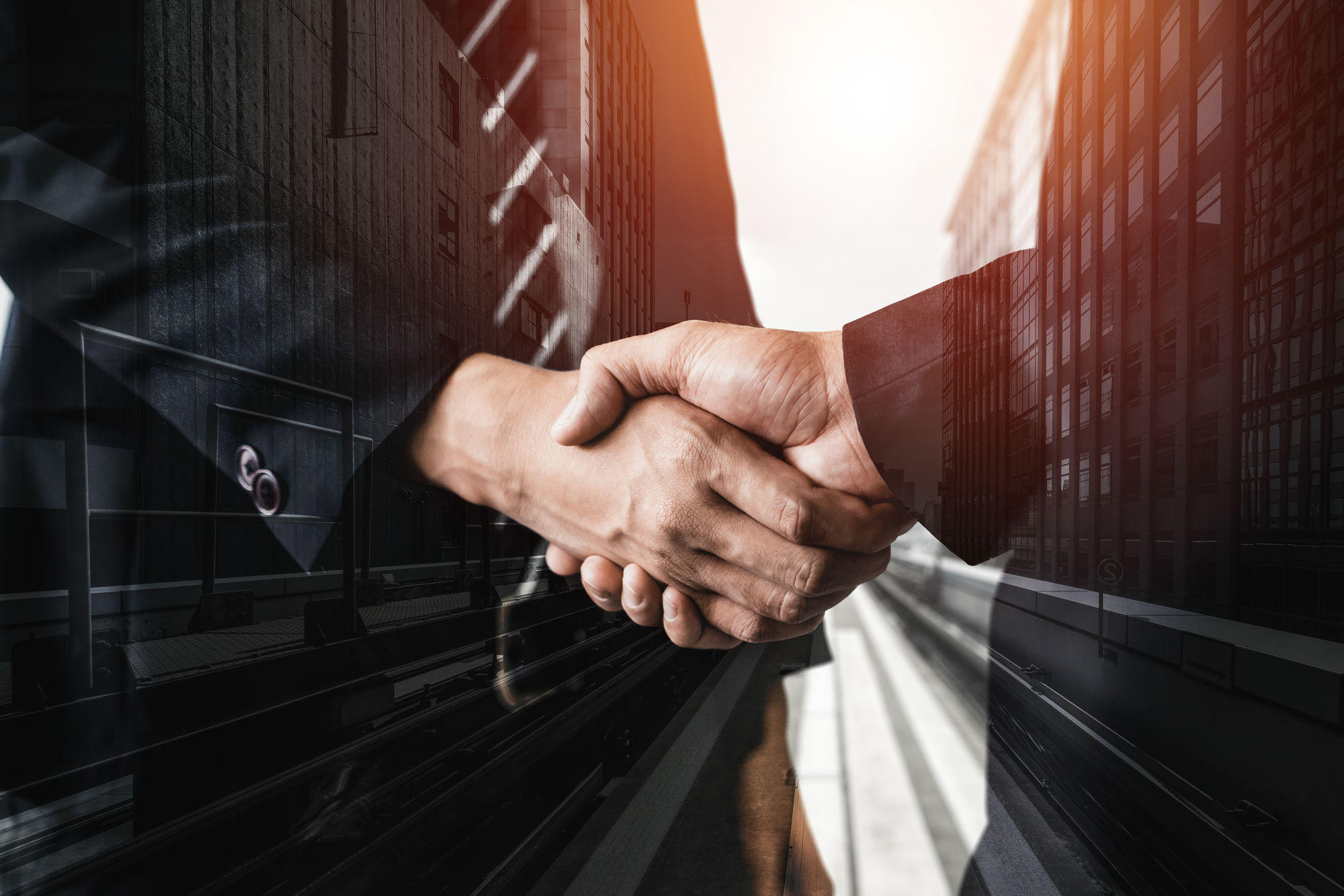 Double exposure image of business people handshake on city office building in background showing partnership success of business deal. Concept of corporate teamwork, trust partner and work agreement.